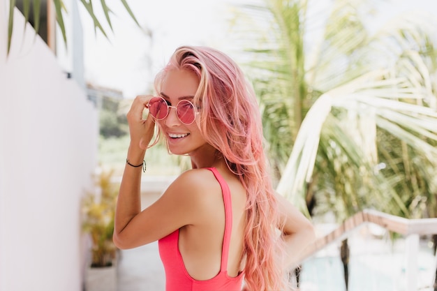 自然のサングラスでポーズをとる長いピンクの髪の女性 無料の写真