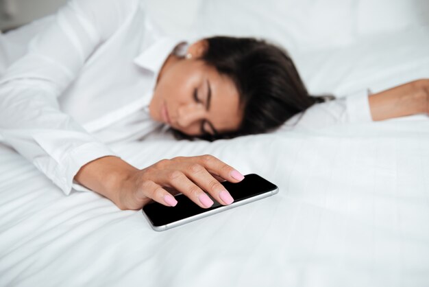 Premium Photo | Woman with mobile phone in hand on bed