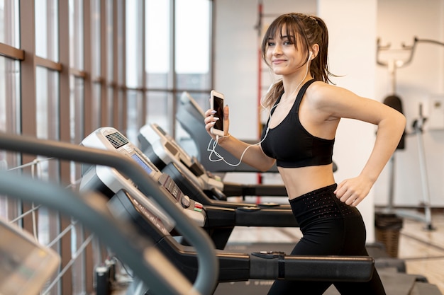 Woman with mobile running on treadmill Premium Photo