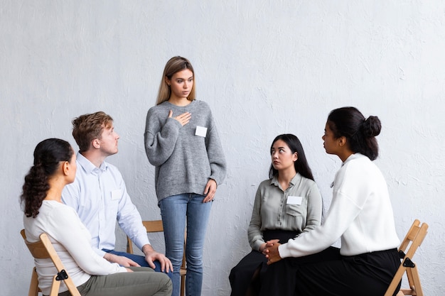 Woman with name tag speaking at a group therapy session Free Photo