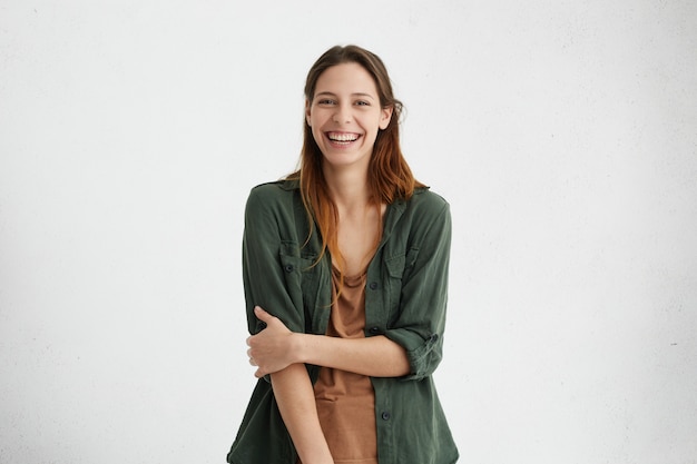 Woman with wide smile dressed in green jacket and brown t-shirt smiling broadly being happy to meet you Free Photo