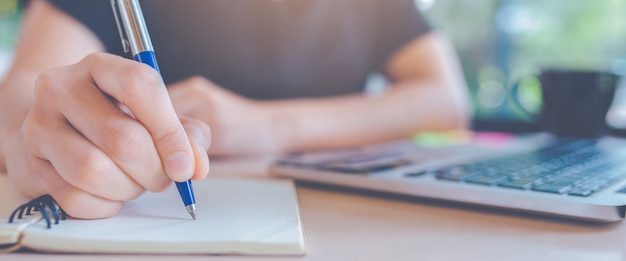 Premium Photo | Woman writing on a notepad with a pen in office