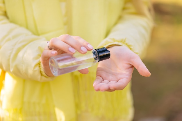 Premium Photo Woman In A Yellow Jacket Treats Hands With An Antiseptic Spray