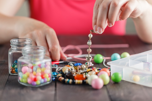 Premium Photo | Womanâ s hands making bracelete with plastic beads