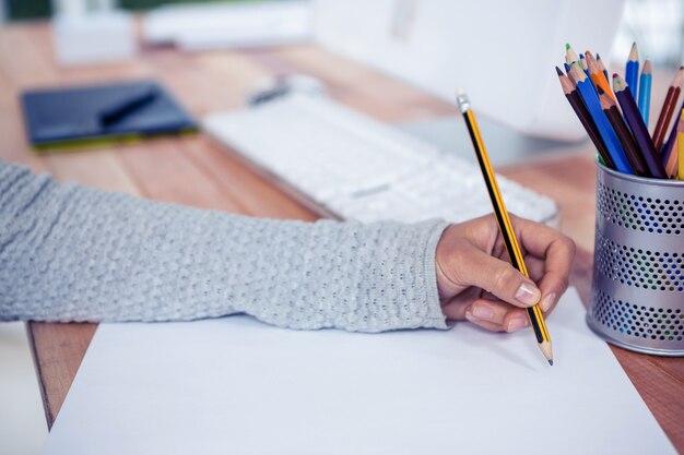 Womans hand drawing with pencil on white sheet in office Premium Photo