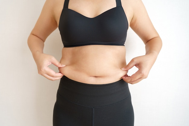 女性の体脂肪腹 過度の腹脂肪を持っている肥満女性の手 ダイエットライフスタイルのコンセプト プレミアム写真