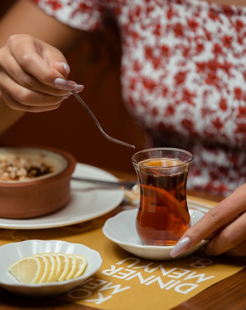 レモンと伝統的なアゼルバイジャングラスで紅茶を飲む女性 無料の写真