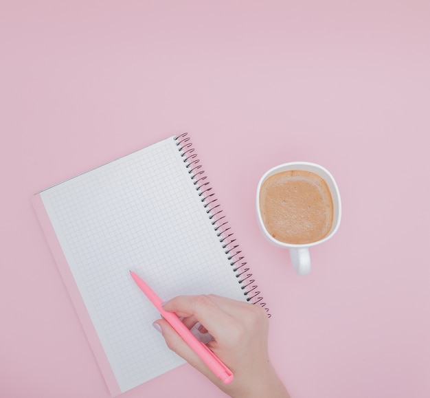 ピンクの背景 インスタグラム ビジネスコンセプトに空白のノートに書く女性の手 プレミアム写真