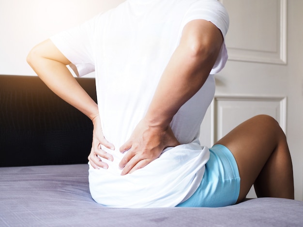 women-suffering-with-back-pain-and-waist-pain-sitting-on-bed-premium