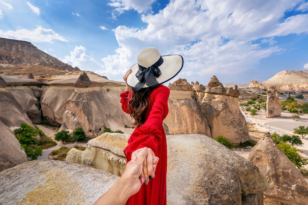 男性の手を握り トルコのカッパドキアにある妖精の煙突に彼を導く女性観光客 無料の写真