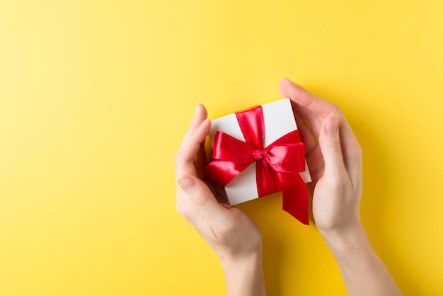 Download Premium Photo Womman S Hand Holding A Gift Box Over Yellow Background Valentines Theme Yellowimages Mockups