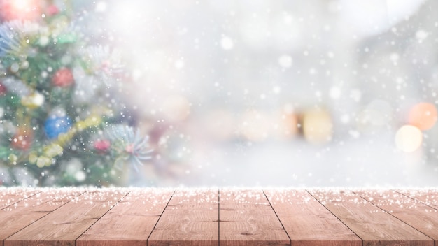 Wood table top on blur with bokeh christmas tree background with snowfall Premium Photo Wood table top on blur with bokeh christmas tree background with snowfall Premium Photo