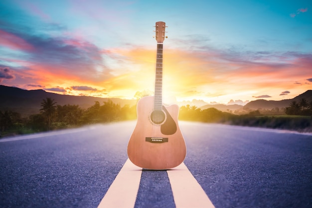 Premium Photo | Wooden acoustic guitar lying on street with sunrise ...