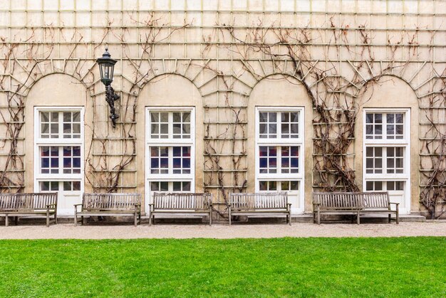 Wooden benches facing the wall with the arched stained-glass windows Premium Photo