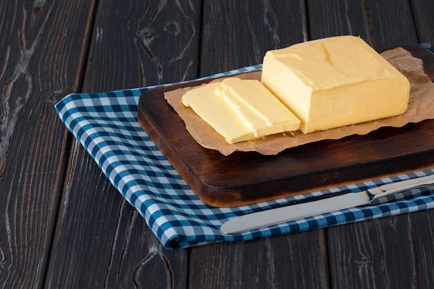 Wooden board with butter on blue checkered napkin 