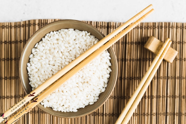 Free Photo Wooden Chopsticks And Cup With White Rice On Bamboo Mat