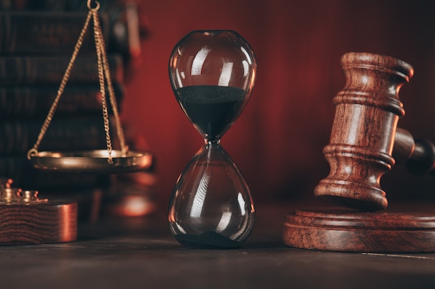 Premium Photo | Wooden gavel, hourglass and scales on wooden table