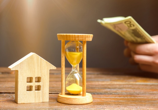 Wooden house and clock. businessman counting money Premium Photo