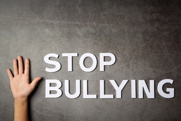 Word "stop bullying" with child's hand on dark wall Free Photo