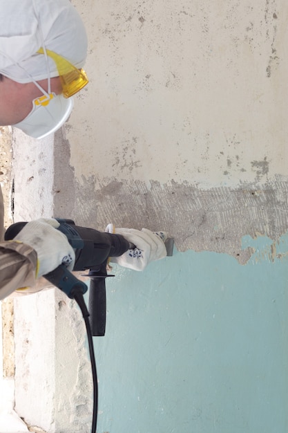 Premium Photo | Worker removes old paint from a concrete wall with a ...