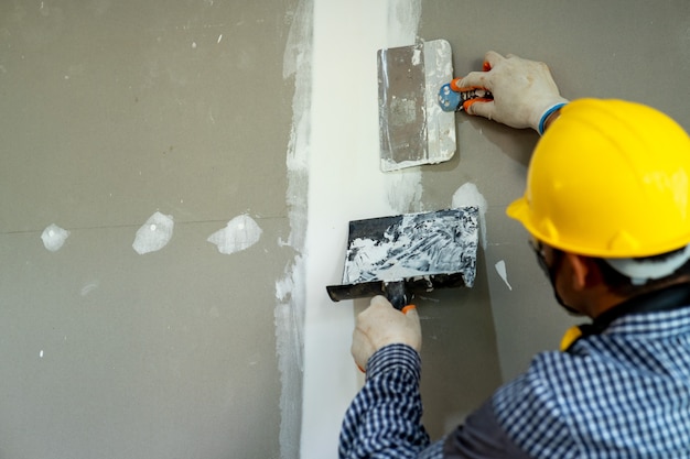 Premium Photo | Worker repairs wall with spackling paste,construction ...