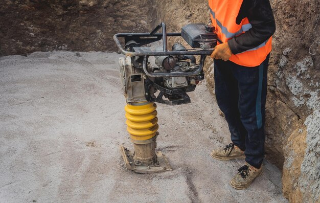 Premium Photo | Worker uses a portable vibration rammer at construction ...