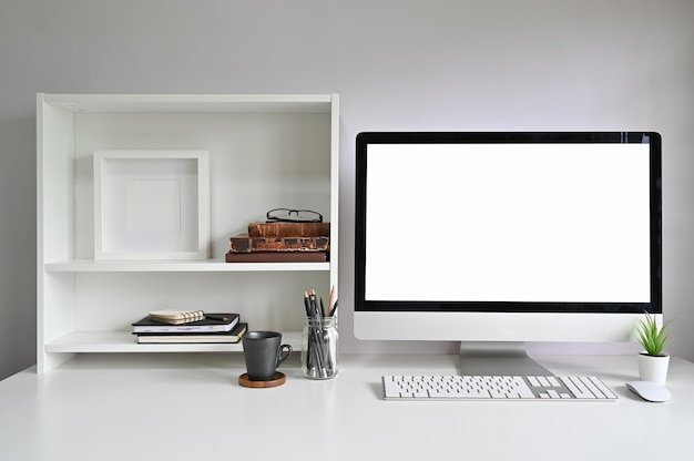 Workspace mockup computer on office desk and books, photo frame and books on shelves. Premium Photo