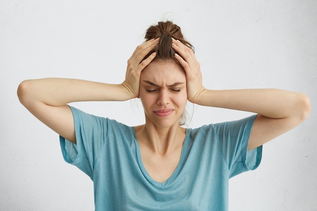 Worried woman closing her eyes with hands on head having headache Free Photo