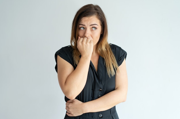 Worried young woman biting nails while having anxiety. Free Photo