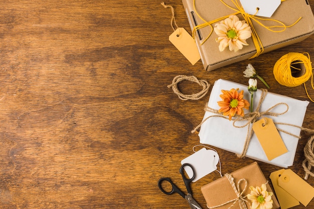 Wrapped gift with empty tag and beautiful flower over wooden table Free Photo