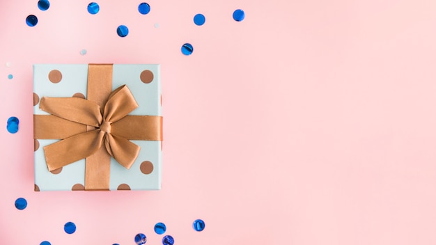 茶色の弓とパステルピンクの背景にリボンでプレゼントを包む プレミアム写真