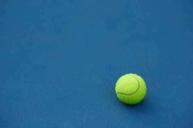 黄色の明るいテニスボールは青いカーペットの背景に横たわっています テニスをするために作られました 青いテニスコート 無料の写真