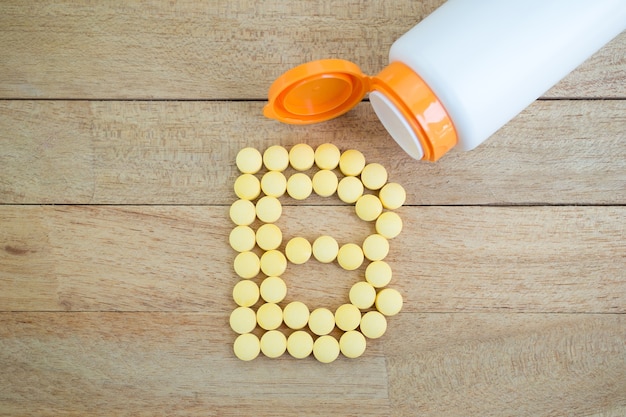 Yellow pills forming shape to b alphabet on wood background Premium Photo