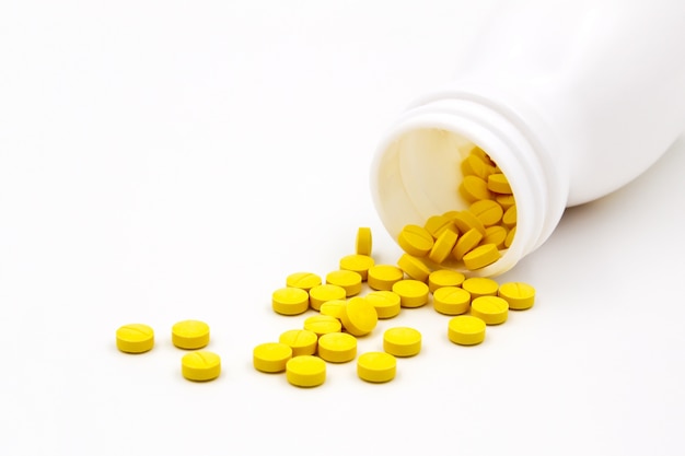 Premium Photo | Yellow pills an pill bottle on white background