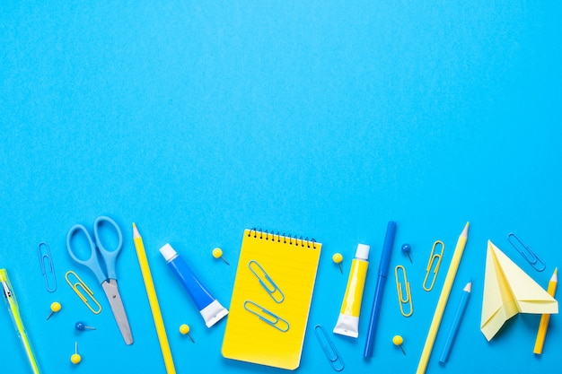 Premium Photo | Yellow school supplies over the blue pastel background.