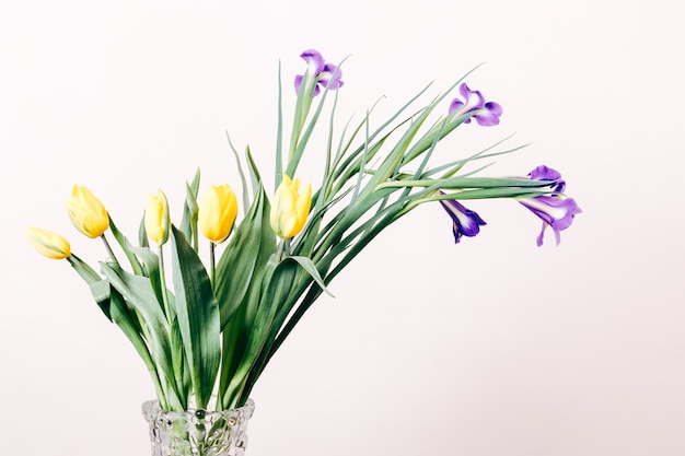Premium Photo | Yellow tulips and purple irises in a vase