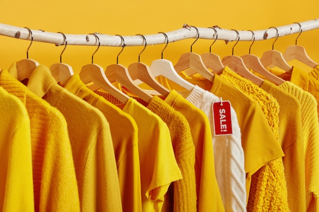 Free Photo | Yellow and white clothes on sale hangings on racks against ...