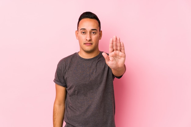 Premium Photo Yooung Latin Man Posing In A Pink Wallstanding With Outstretched Hand Showing Stop Sign Preventing You