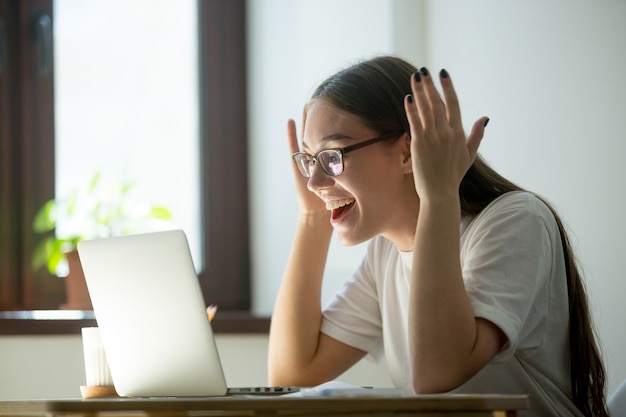 Giovane donna adulta riceve buone notizie tramite il suo computer portatile Foto Gratuite