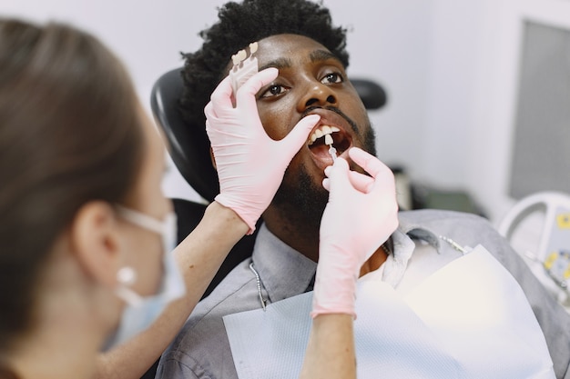 Young african-american man. guy visiting dentist's office for prevention of the oral cavity. man and famale doctor while checkup teeth. Free Photo