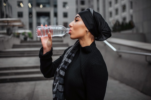 Young arabian woman drinking water from plastic bottle Premium Photo