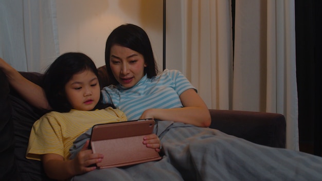 Young asian family and daughter happy using tablet at home. korean mother  relax with little girl