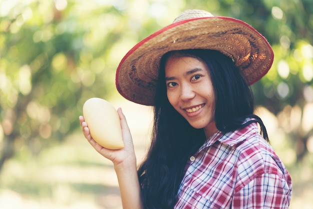 Young asian farmer picking mango fruit in organic farm Premium Photo