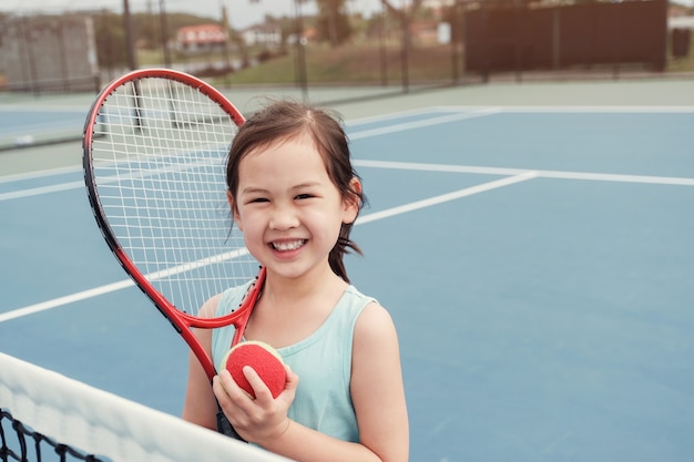 Young asian girl tennis player on outdoor blue court | Premium Photo