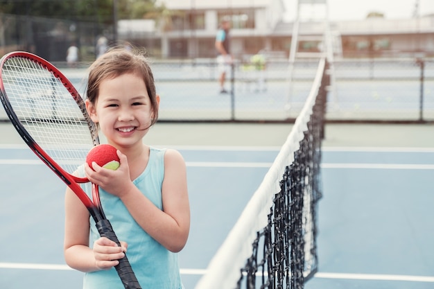 Premium Photo | Young asian girl tennis player on outdoor blue court