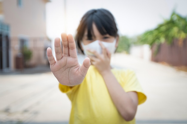 Premium Photo | Young asian girl wearing mask for protect covid 19, thai  kid wear dust mask. for protect pm2.5 and show stop hands gesture for stop  corona virus outbreak.