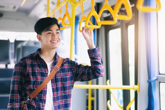 Premium Photo | Young asian man holding handle of the public bus.