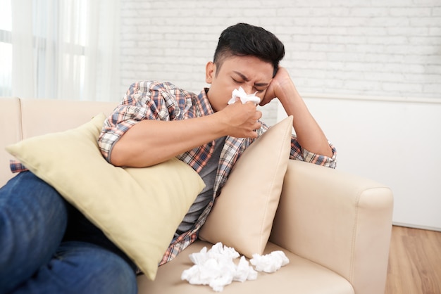 Young asian man suffering runny nose having medical leave staying at home Free Photo