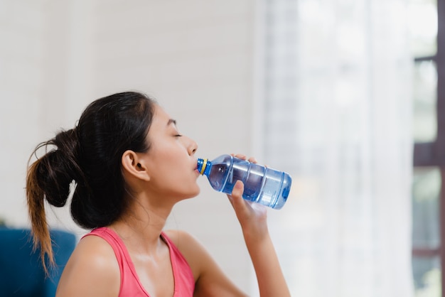 Free Photo | Young asian woman drinking water because feel exhausted rest  after exercise in living room