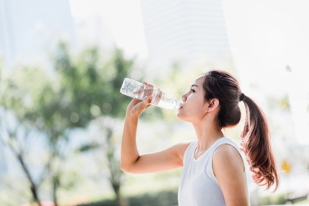 Premium Photo | Young asian woman drinking water from water bottle after  jogging in the park